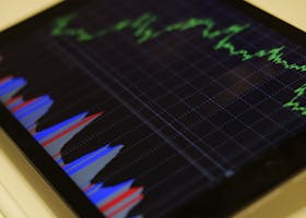 Close-up of a tablet displaying stock market analysis with colorful graphs.